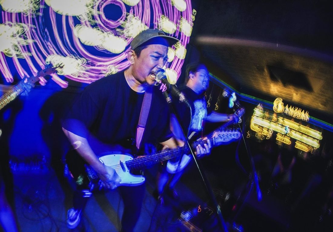 Vokalis dan gitaris Hardmilk di bawah lampu biru